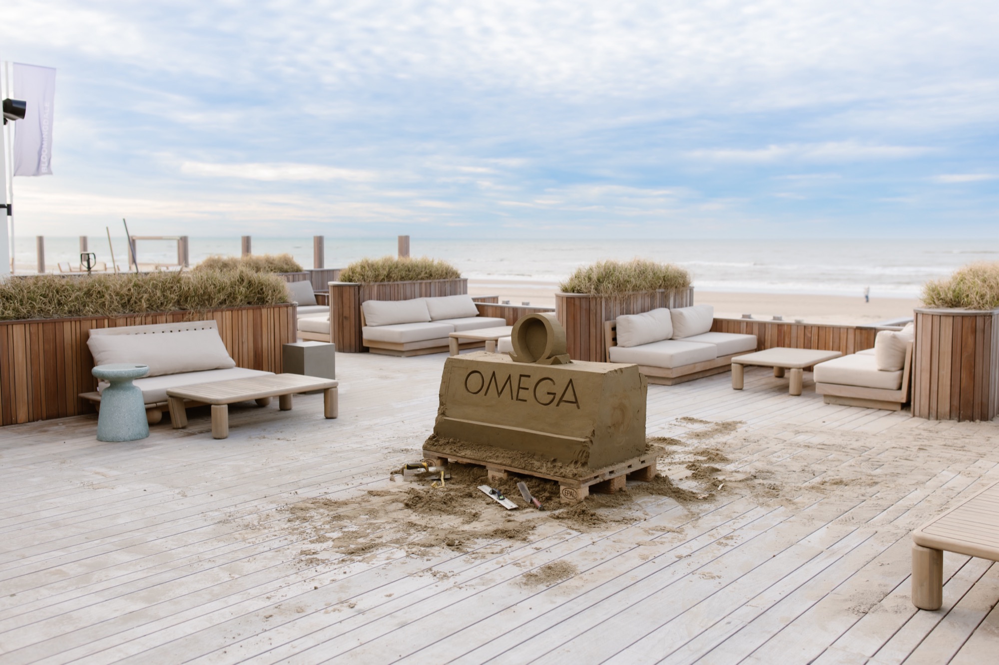 Sand sculpture with OMEGA logo on the deck of a beach pavilion