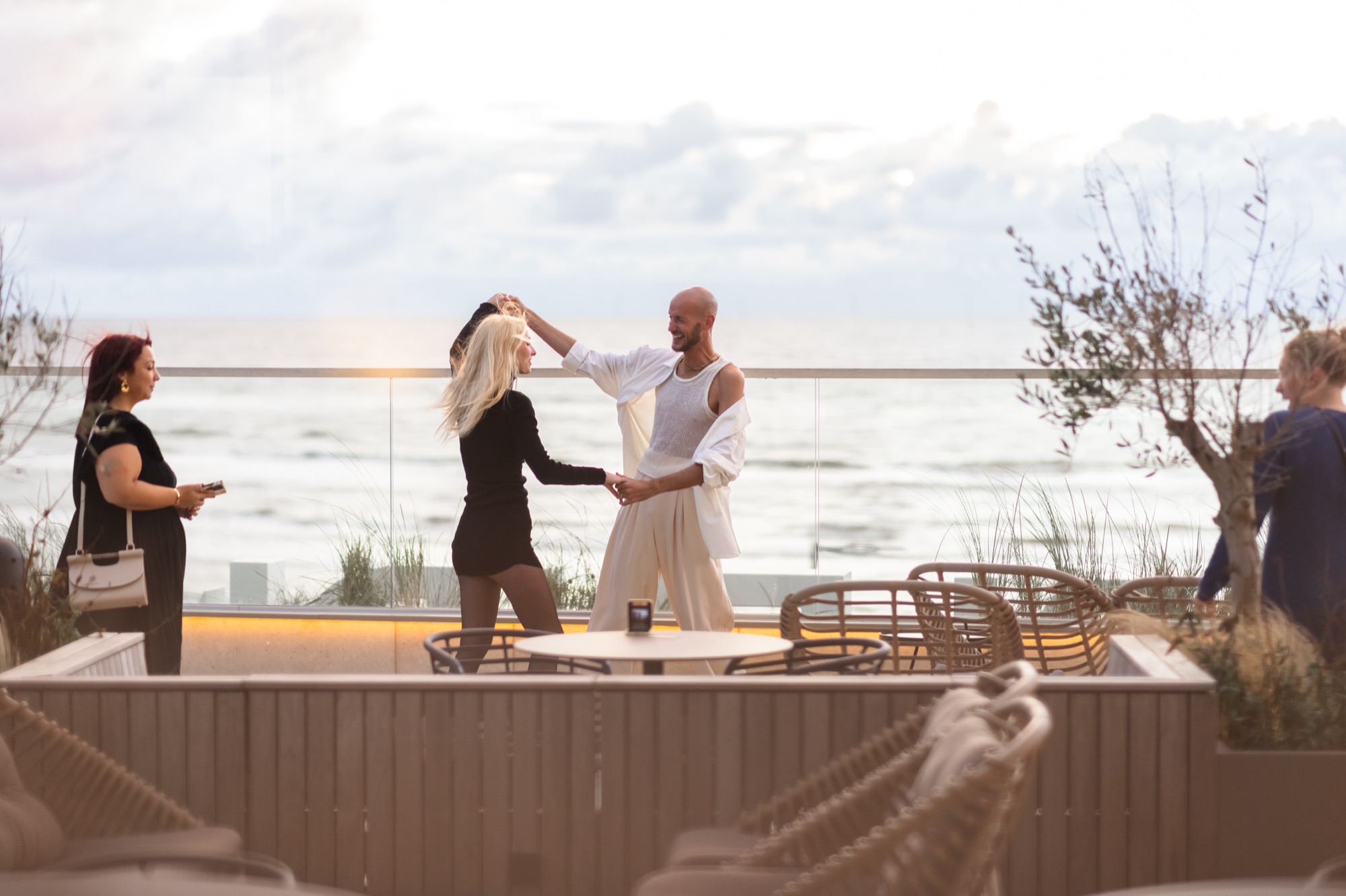 Gasten dansen bij zonsondergang op het terras aan zee